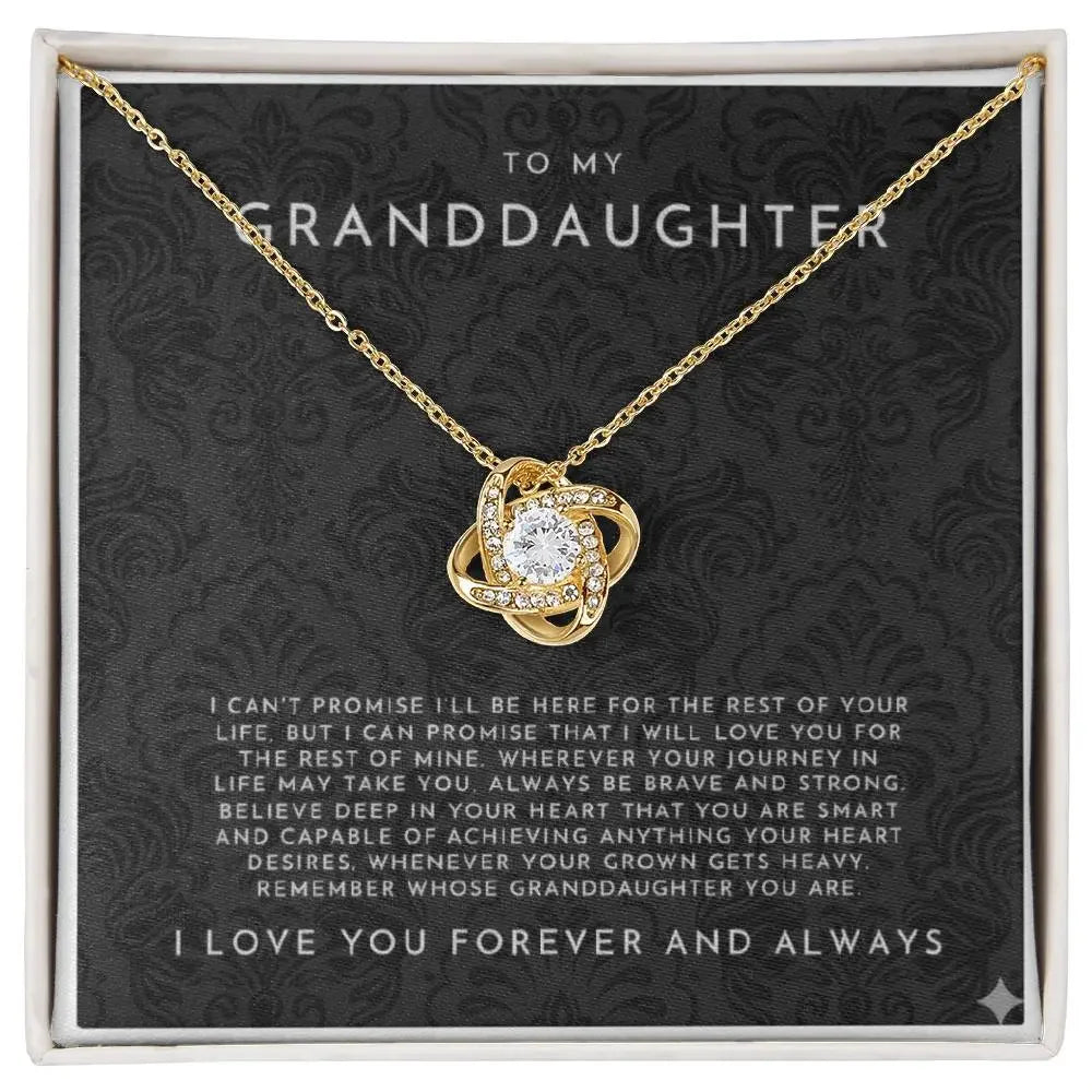 Gold necklace with intricate knot pendant and central clear gemstone, displayed on a black card reading to my granddaughter with loving message